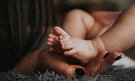 woman holding new boarn baby's feet in her hand